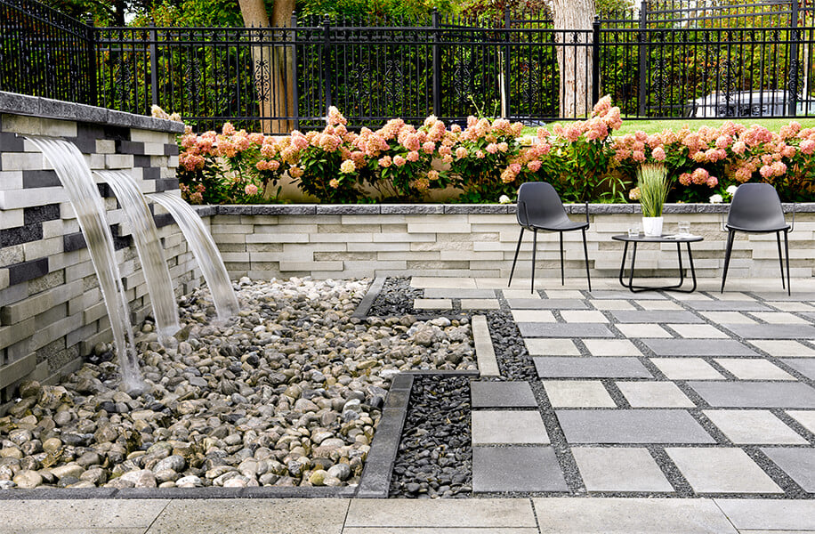 Patio trasero con losas de patio Industria Polished y un elemento acuático