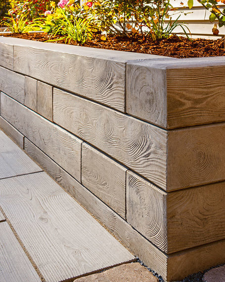 Muro de contención Borealis de Techo-Bloc utilizado para crear un jardín que actúa como borde de camino en un diseño de paisaje.